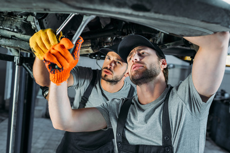 professional auto mechanics working with car and tools in workshopの写真素材
