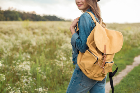 cropped shot of woman with yellow backpack standing in fieldの写真素材