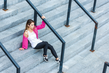 high angle view of stylish asian woman sitting on stairs at urban streetの写真素材