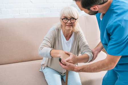 cropped shot of male nurse helping senior woman with walking stickの写真素材