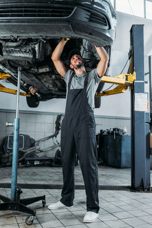 professional worker in uniform repairing a car in mechanic shopの写真素材