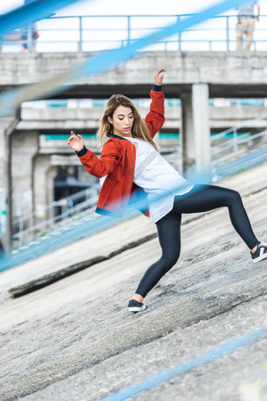 selective focus of young asian stylish female urban dancer dancing at city streetの写真素材
