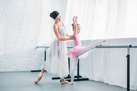 young ballet teacher exercising with cute little student in ballet studioの写真素材