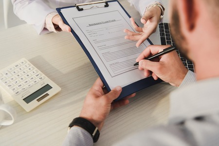 cropped view of client signing insurance claim form in medical officeの写真素材