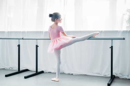 back view of little child in pink tutu exercising in ballet schoolの写真素材