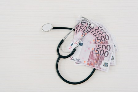 top view of stethoscope and euro banknotes on table in clinic, health insurance conceptの写真素材