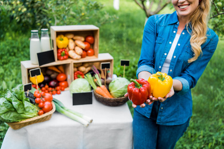 cropped image of farmer showing ripe bell peppers at farmer market