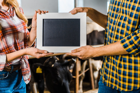 cropped image of farmers showing blackboard in stableの写真素材