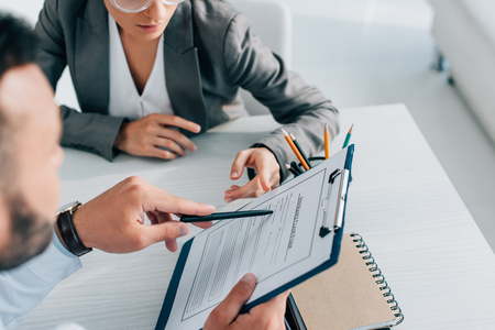 cropped image of doctor pointing on insurance claim form to patient in clinicの写真素材