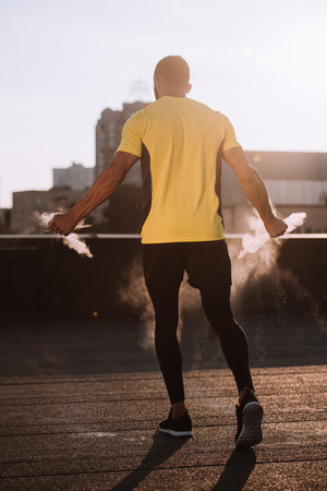 back view of sportsman with talc powder in hands standing on roofの写真素材