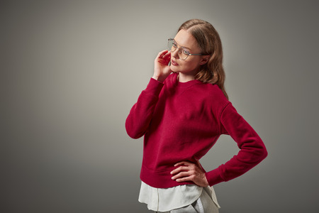 beautiful woman in stylish red sweater and eyeglasses looking away isolated on greyの写真素材