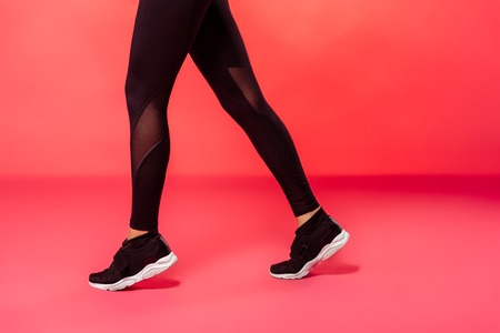 cropped image of sportswoman walking in black leggings on redの写真素材