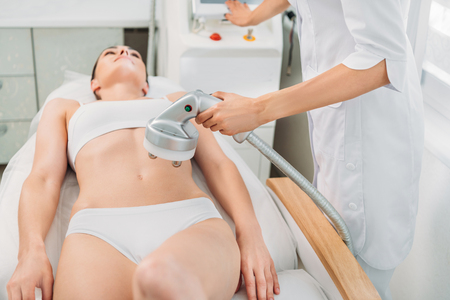attractive woman getting electrical massage made by cosmetologist in spa salonの写真素材