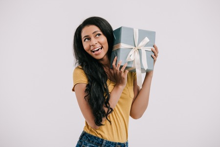 smiling african american girl listening present box isolated on whiteの写真素材