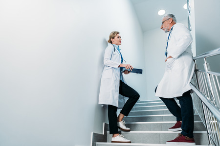 side view of male and female doctors talking on staircase in hospitalの写真素材