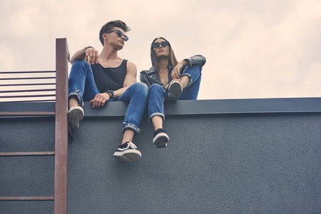 bottom view of interracial young couple in sunglasses sitting on roofの写真素材