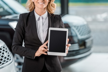 cropped shot of female car dealer holding tablet with blank screen at showroomの写真素材