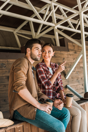 cowboy and cowgirl sitting with coffee to go at ranch, woman pointing on somethingの写真素材