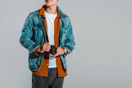 cropped view of young stylish tourist holding photo camera isolated on greyの写真素材