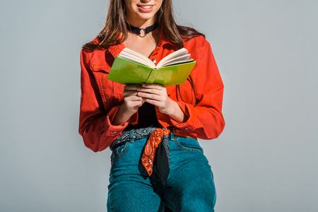 cropped view of female student reading book isolated on greyの写真素材