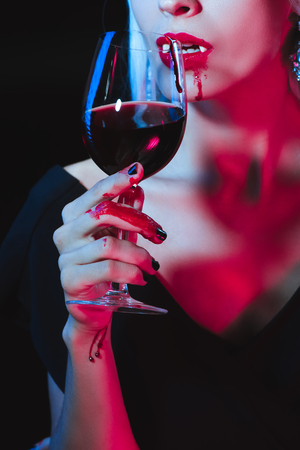 cropped view of vampire drinking blood from wineglass isolated on blackの写真素材