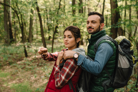 man hugging woman while hiking in forest togetherの写真素材