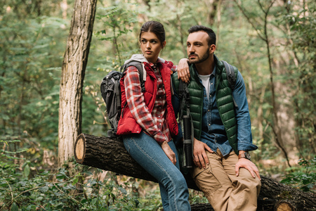 young travelers resting on log while hiking in forestの写真素材