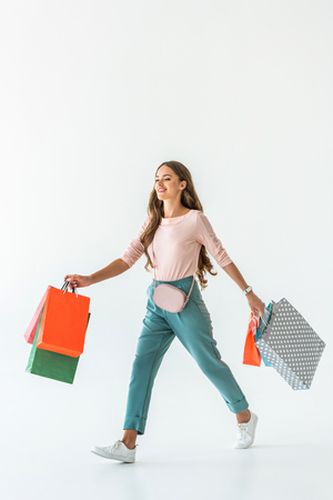 beautiful happy woman walking with shopping bags, isolated on whiteの写真素材