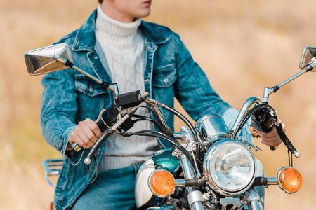 cropped view of stylish young man on retro motorbikeの写真素材