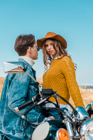 boyfriend sitting on retro motorbike while beautiful girlfriend looking at cameraの写真素材