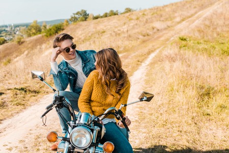 couple sitting on retro motorbike and looking at each otherの写真素材