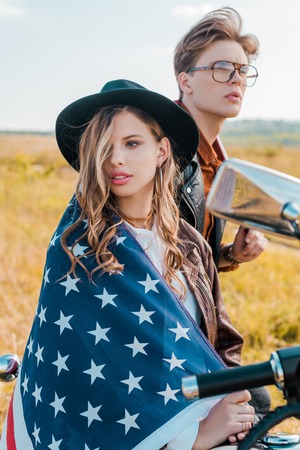 young couple with american flag sitting on motorbike, independence day conceptの写真素材