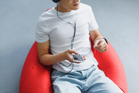 cropped shot of young man using smartphone and listening music in headphonesの写真素材