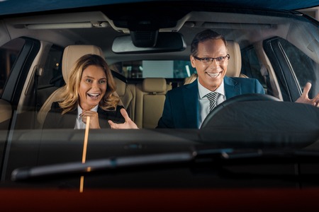 portrait of cheerful business couple in new car for test drive