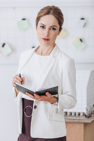 beautiful confident businesswoman in formal wear working with diary in modern officeの写真素材