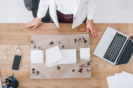 cropped view of architect working with house model at workplace