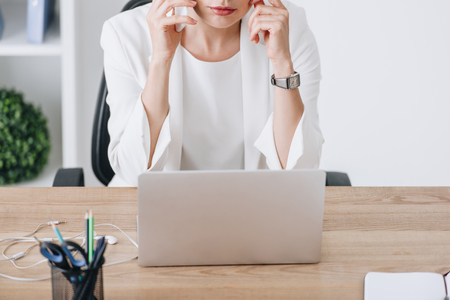 cropped view of businesswoman working with smartphone and laptop at workplaceの写真素材
