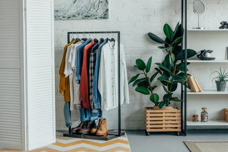 different shirts on hangers, shoes on shelf in living roomの写真素材