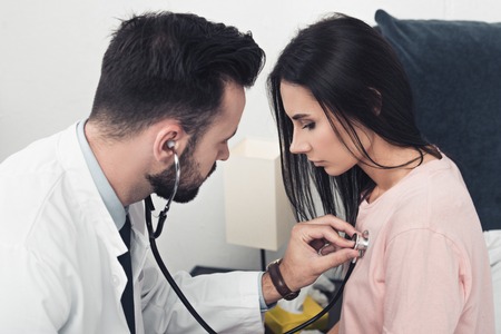 close-up shot of doctor listening breath of female patientの写真素材