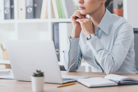 cropped shot of thoughtful adult businesswoman sitting at workplaceの写真素材
