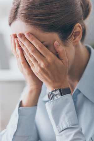 close-up shot of stressed adult businesswoman covering face with handsの写真素材