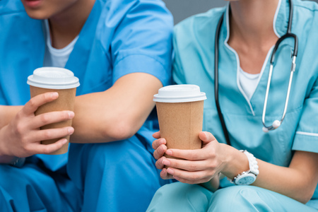 cropped image of medical students holding disposable coffee cupsの写真素材