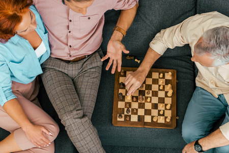 cropped shot of old friends playing chess together at homeの写真素材