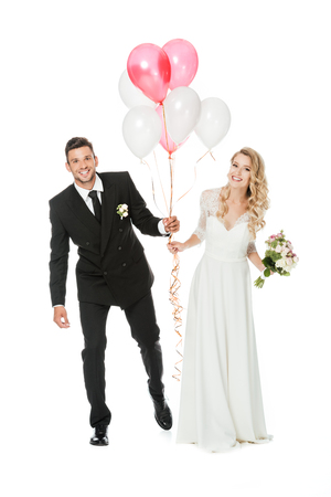 happy young bride and groom with air balloons isolated on whiteの写真素材