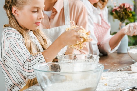 cropped shot of adorable little child making dough with parents at homeの写真素材