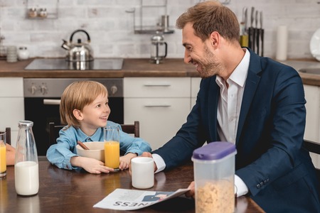 father and son laughing together at kitchen during breakfastの写真素材