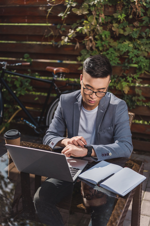 asian businessman checking time while remote working in cafeの写真素材