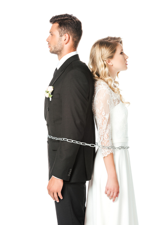 young newlyweds tied with chain back to back isolated on whiteの写真素材