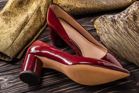 close up view of stylish red female shoes and golden clothing on wooden surfaceの写真素材