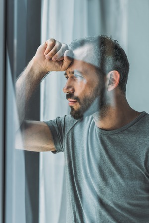 side view of sad bearded man looking at windowの写真素材